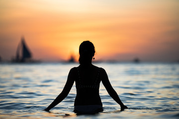 Silhouette eines Mädchens, das einen atemberaubenden Sonnenuntergang am White Beach von Boracay bewundert. Der White Beach de Boracay liegt an Station 1, dem Zentrum der Insel. Philippinen.