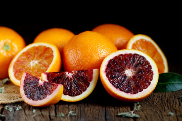 Sliced Sicilian Blood oranges fruits over old dark wooden background. Top view.
