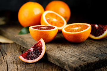 Sliced Sicilian Blood oranges fruits over old dark wooden background. Top view.