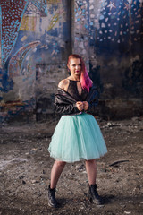 Portrait of a young girl with pink hair standing inside of collapsed building surrounded by ruins