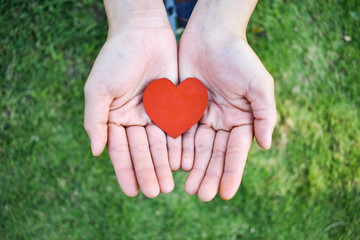 Obraz premium A red heart cut from paper in a woman's hand