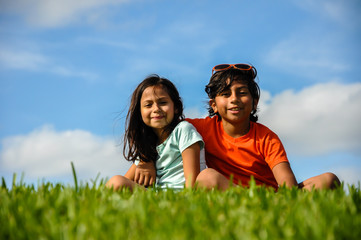 young brother sister boy arm around girl free education, fafsa, universal income approved, sitting indian style grass happy learning, freedom