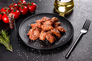Chicken fillet in sesame seeds, teriyaki sauce on a black stone plate