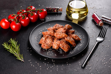 Chicken fillet in sesame seeds, teriyaki sauce on a black stone plate