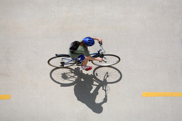 Girl riding a bicycle on a bike path taken from above