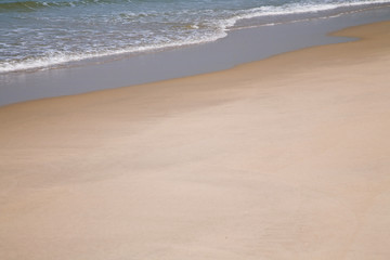 Close up shot of the piece of sandy beach with sea waves rolling over it. Natural background. Marine theme. Wallpaper.