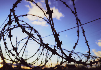 Barbed wire against the sky with clouds