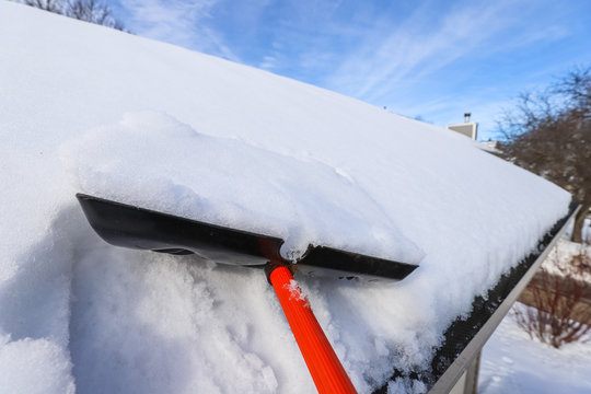 Heavy Snow On Roof Being Shoveled Off To Prevent Ice Dams And Roof Damage