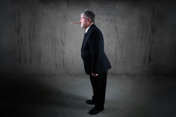 Lying businessman with a long nose standing in a suit, liar concept