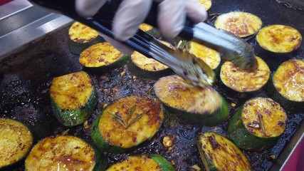 Roasting round slices of zucchini, vegetarian cuisine. The cook flips the fried slices to the other side.