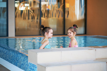 Adorable little girls play and swim in pool during the holidays