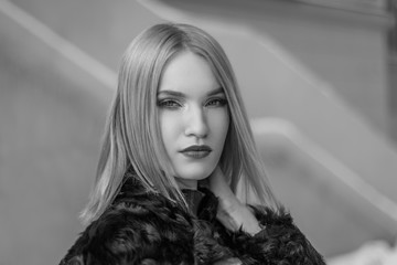 young attractive woman in a fur coat on the street. portrait of a beautiful girl in winter in the...