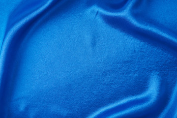 Blue silk background with a folds.  Abstract texture of rippled satin surface