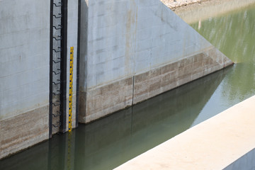 Closeup of a part of concrete dam and water level  measuring tool.