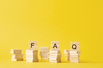 Wooden blocks with word FAQ on the yellow baclground. Frequently asked question concept