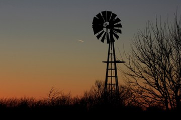 Kansas colorful Sunset with tree's,clouds, and a Windmill silhouette north of Hutchinson Kansas USA out in the country.