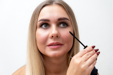 Beautiful blonde woman paints eyelashes. Beautiful female face. Makeup Read More Beauty girl with perfect skin. Makeup in progress