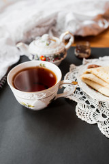 Obraz na płótnie Canvas A beautiful version of Breakfast with a white porcelain Cup and a painted teapot in the background, ready-made pancakes on a saucer. Table setting for the Russian holiday Maslenitsa