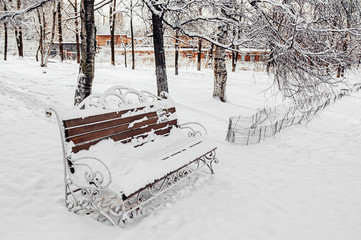 Very beautiful wood and metal bench on a winter snow day. Fresh fluffy untouched snow in the city...