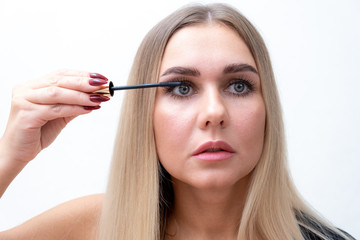 Fototapeta premium Beauty Cosmetics. Closeup Of Beautiful Sexy Woman Putting Black Mascara On Long Thick Eyelashes With Brush. Fashionable Female Model With Soft Skin, Perfect Makeup And Fake Eyelashes. High Resolution.