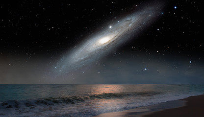 Andromeda Galaxy over the sea with sunset reflection on the sea 