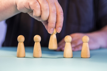 Man selecting wooden pieces representing characters. People choice concept. Recruitment concept -...