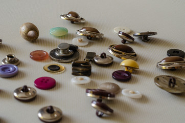 Obraz na płótnie Canvas Various sewing accessories close-up. Various sewing accessories close-up. Used multi-colored buttons on a light textured surface. Side view. Focus in the background. Eye level shooting.