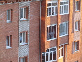 Modern brick residential building close-up. Perspective view of a house wall with windows and balconies. Facade of a brick urban apartment building.