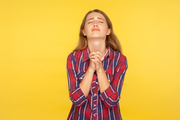 Please I'm begging! Portrait of despaired ginger girl in shirt keeping arms in prayer gesture and...
