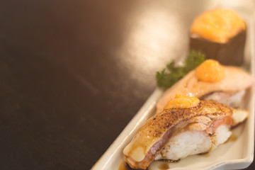 Close-up Salmon aburi nigiri and gunkan sushi with saikyo sauce on white plate in Japanese restaurant. Copy space wallpaper.
