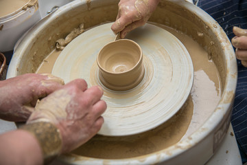 Hands of the master and girl mold from clay on the potter's wheel