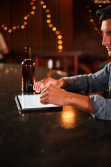 people and technology concept - happy man with smartphone drinking beer and reading message at bar or pub