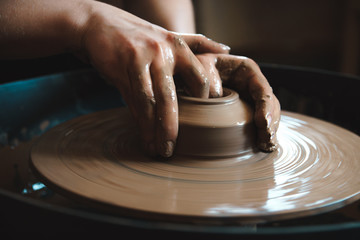 Pottery concept. Professional ceramist working with clay at throwing table in workshop.