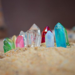 Multicolored crystal quartz sticks of gems protrude from the sand