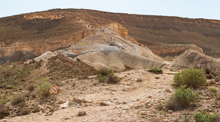 a distant hiking group on the steep ascent of the divshon mountain in the zin valley near Sde Boker in Israel from the midreshet ben gurion serpentine road