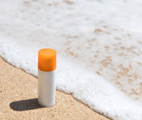 Bottle of sunscreen lotion on the sandy beach by the sea