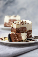 A bite from a piece of homemade raw chocolate cheesecake or mousse cake on white plate, vertical orientation, copy space