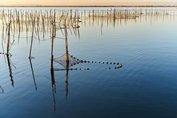 the sunset with fishing nets on a lake