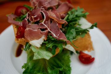 Delicious green salad with jamon and vegetables on a plate served in restaurant