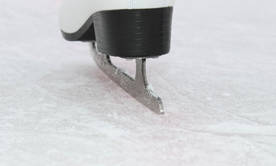 Figure Skates on the foot on the ice close-up. The skate blade from the back.