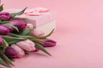 a bouquet of pink tulips and a gift box for women's day on a pink background. Mother's day greetings