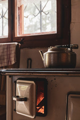 old stove with open hatch and a kettle in a cabin