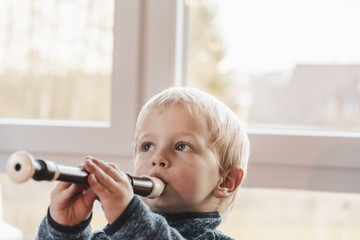 infant boy playing flute - obrazy, fototapety, plakaty