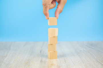 Close-up hand choose a cube shape wooden block toy stacked without graphics for Business design concept and activity for child foundation practice skills.