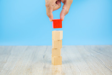 Close-up hand choose a cube shape wooden block toy stacked without graphics for Business design concept and activity for child foundation practice skills.