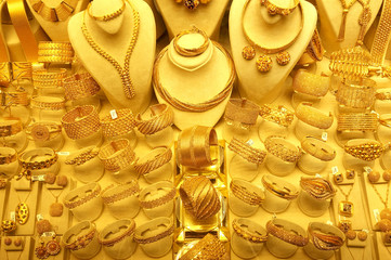 Many gold jewelry and rings on stands. 