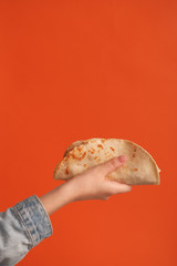 Mexican national food taco or Tatar national food kystyby in hand on an orange background.Food in a tortilla.National food concept