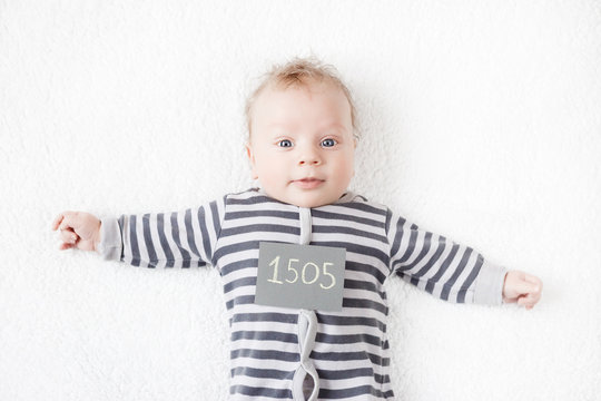 portrait of a cute baby in a striped suit with a sign on his chest