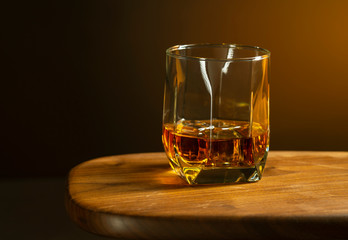 Whiskey in a glass with ice cubes on a wooden table