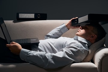 Fototapeta premium businessman is lying on the sofa with laptop and resting